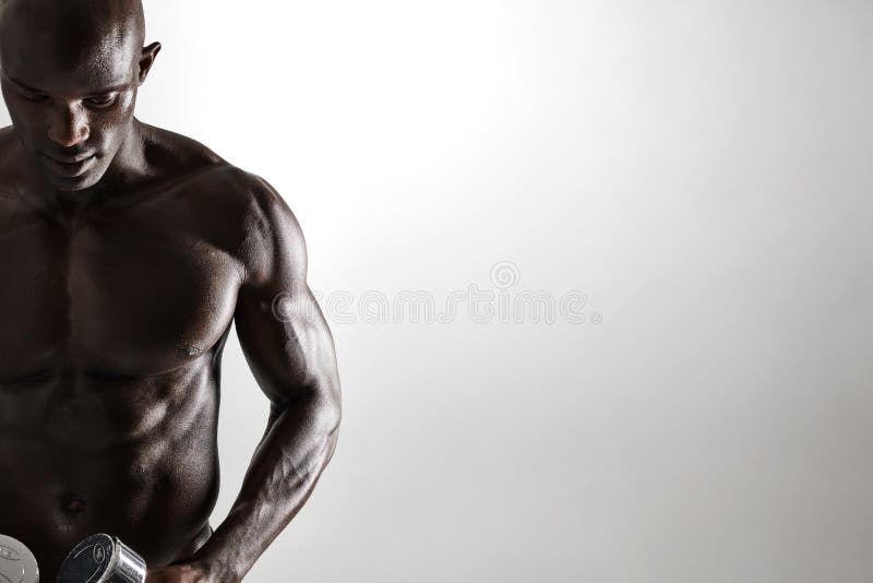 Gesunder muskulöser junger Mann, der Dummköpfe hält lizenzfreies stockbild Gesunder muskulöser junger Mann, der Dummköpfe hält lizenzfreies stockbild
