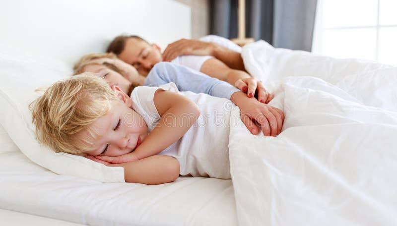 Gesunder Schlaf. glückliche Familieneltern und Kinder, die im weißen Bett schlafen. lizenzfreie stockbilder
