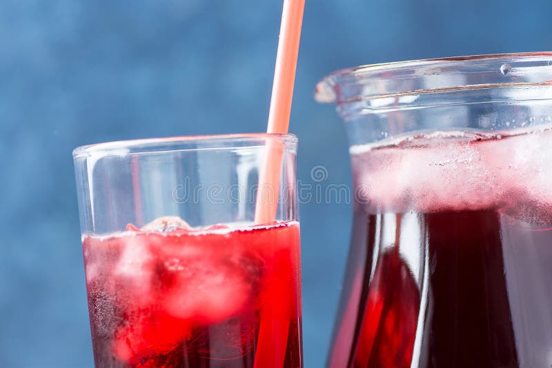Gesundes Auffrischungsgetränk von den Eis-Hibiscus-Tee-und Rot-Beeren und vom Fruchtsaft im Pitcher und im hohen Glas mit Stroh V stockfotografie Gesundes Auffrischungsgetränk von den Eis-Hibiscus-Tee-und Rot-Beeren und vom Fruchtsaft im Pitcher und im hohen Glas mit Stroh V stockfotografie