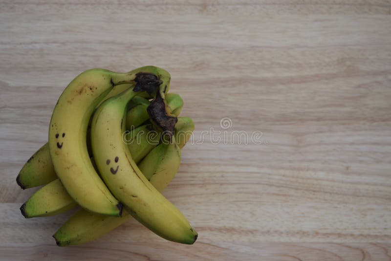 Gesundes Lebensmittelphotographiebild mit frischer Frucht von Bananen mit gezogenem auf glücklichem Lächeln auf rustikalem hölzer lizenzfreie stockfotos Gesundes Lebensmittelphotographiebild mit frischer Frucht von Bananen mit gezogenem auf glücklichem Lächeln auf rustikalem hölzer lizenzfreie stockfotos