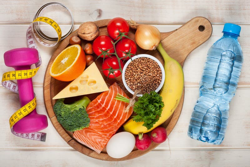 Healthy lifestyle concept. Dumbbell, bottle of water and healthy organic food on wooden table. Healthy lifestyle concept. Dumbbell, bottle of water and healthy organic food on wooden table