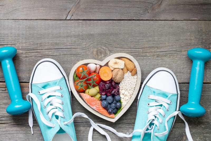 Healthy lifestyle concept with food in heart and sports fitness accessories on wooden board. Healthy lifestyle concept with food in heart and sports fitness accessories on wooden board