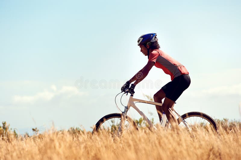 Cyclist man riding mountain bike in field horizontal view of healthy lifestyle. Cyclist man riding mountain bike in field horizontal view of healthy lifestyle