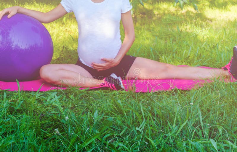 Gesundes übendes Yoga der schwangeren Frau in der Natur draußen Zukünftige Mutter, die Übungen ausdehnend tut Pränatales Yoga und lizenzfreie stockfotos Gesundes übendes Yoga der schwangeren Frau in der Natur draußen Zukünftige Mutter, die Übungen ausdehnend tut Pränatales Yoga und lizenzfreie stockfotos