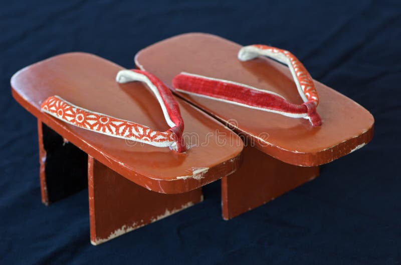 Pair of lacquered vintage geta shoes on black velvet background; these tall sandals are traditionally worn by the geisha. Pair of lacquered vintage geta shoes on black velvet background; these tall sandals are traditionally worn by the geisha