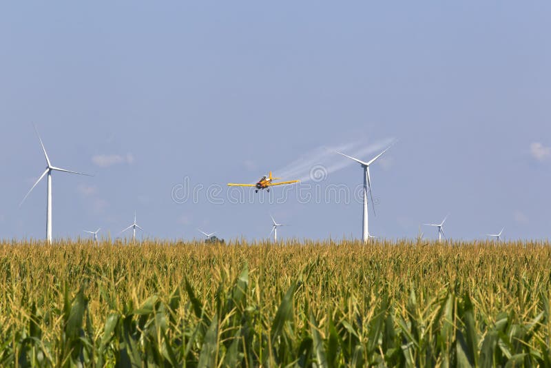 A agricultural plane dusts crops against a blue sky. A agricultural plane dusts crops against a blue sky