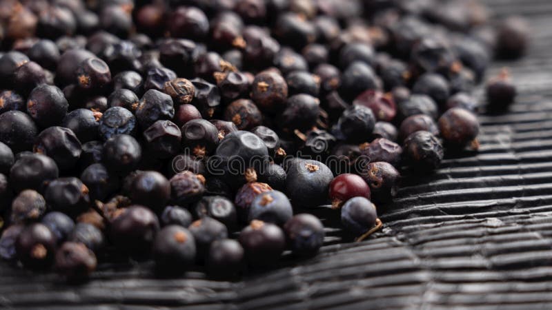 Getrocknete Wacholderbeeren auf schwarzem Papier. dehydrierter aromatischer Wirkstoff.