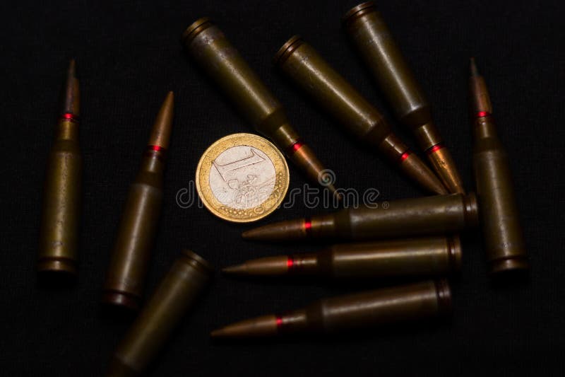 Geweer munitie rond één euro muntstuk op zwarte achtergrond Symboliseert de oorlog voor geld en één van de wereld` s problemen stock fotografie Geweer munitie rond één euro muntstuk op zwarte achtergrond Symboliseert de oorlog voor geld en één van de wereld` s problemen stock fotografie
