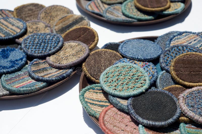 Beverage mats in various colors made from carpet sections are laid out to dry on trays at an outdoor bar. Beverage mats in various colors made from carpet sections are laid out to dry on trays at an outdoor bar