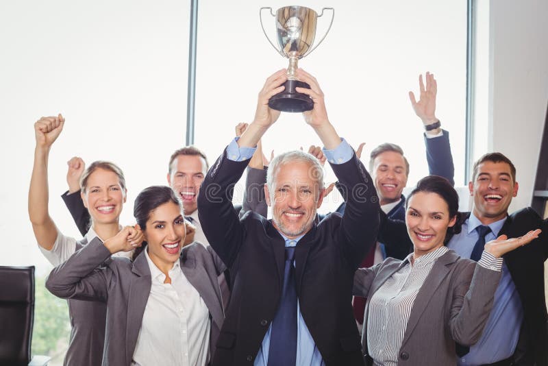 Gewinnendes Geschäft team mit einer haltenen Exekutivtrophäe lizenzfreies stockbild Gewinnendes Geschäft team mit einer haltenen Exekutivtrophäe lizenzfreies stockbild
