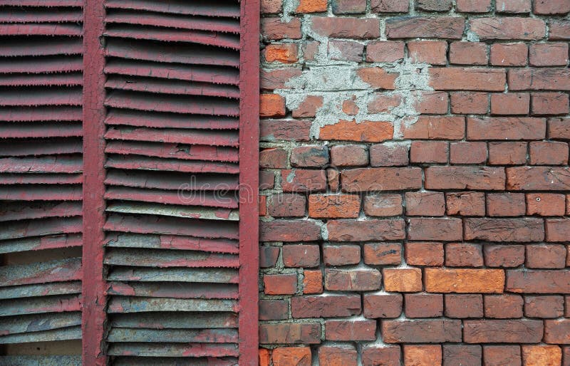 Gewogene Ziegelwand mit Peeling und rostenden Fensterläden lizenzfreies stockfoto