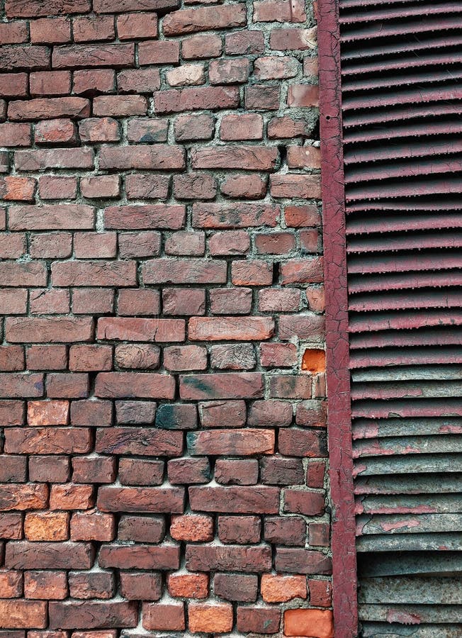 Gewogene Ziegelwand mit Peeling und rostenden Fensterläden stockfoto