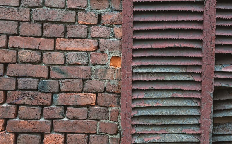 Gewogene Ziegelwand mit Peeling und rostenden Fensterläden stockfotografie