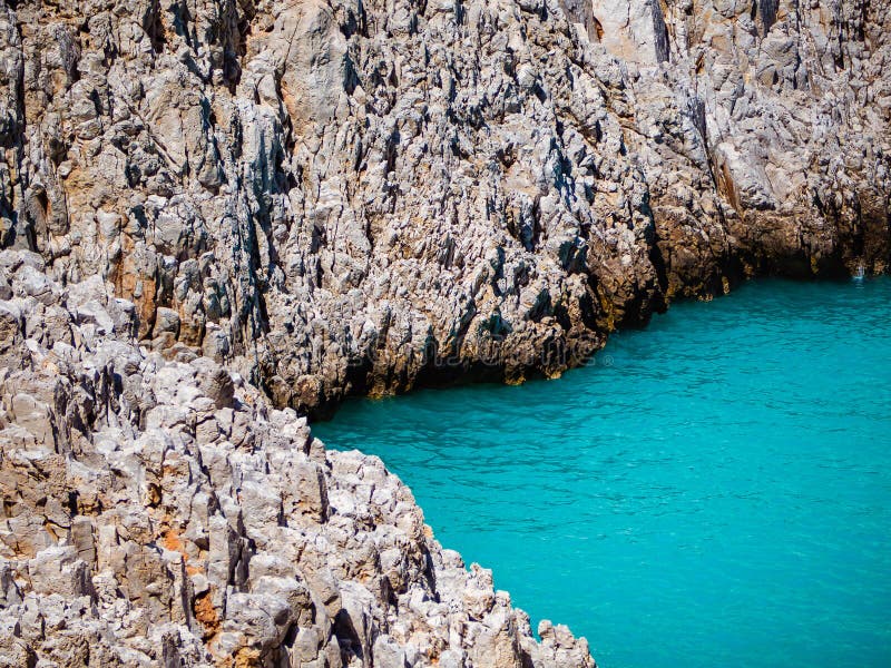 Gezackte felsige Klippen gerade am abgelegenen Strand mit erhabenem blauem Wasser lizenzfreies stockfoto Gezackte felsige Klippen gerade am abgelegenen Strand mit erhabenem blauem Wasser lizenzfreies stockfoto