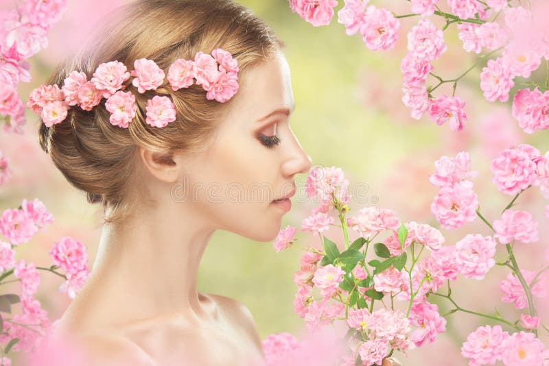 Gezicht van jonge mooie vrouw met roze bloemen in haar haar