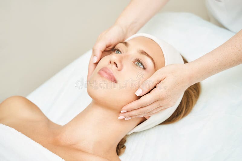 Face massage at spa salon. Doctor hands. Pretty female patient. Beauty treatment. Healthy skin procedure. Young woman head. Light background. Scrub rejuvenation. Facial dermatology mask. Detox therapy. Face massage at spa salon. Doctor hands. Pretty female patient. Beauty treatment. Healthy skin procedure. Young woman head. Light background. Scrub rejuvenation. Facial dermatology mask. Detox therapy