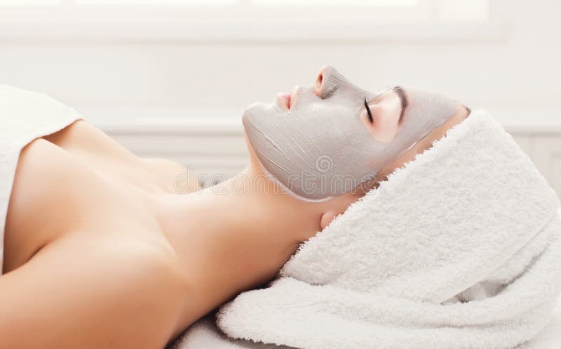 Face mask, spa beauty treatment. Woman applying facial clay mask at spa salon, skincare, side vies. Face mask, spa beauty treatment. Woman applying facial clay mask at spa salon, skincare, side vies