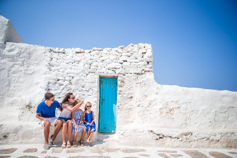 Gezinsvakantie in Europa Ouders en kinderen op straat van typisch grieks traditioneel dorp met witte muren en kleurrijk stock fotografie Gezinsvakantie in Europa Ouders en kinderen op straat van typisch grieks traditioneel dorp met witte muren en kleurrijk stock fotografie