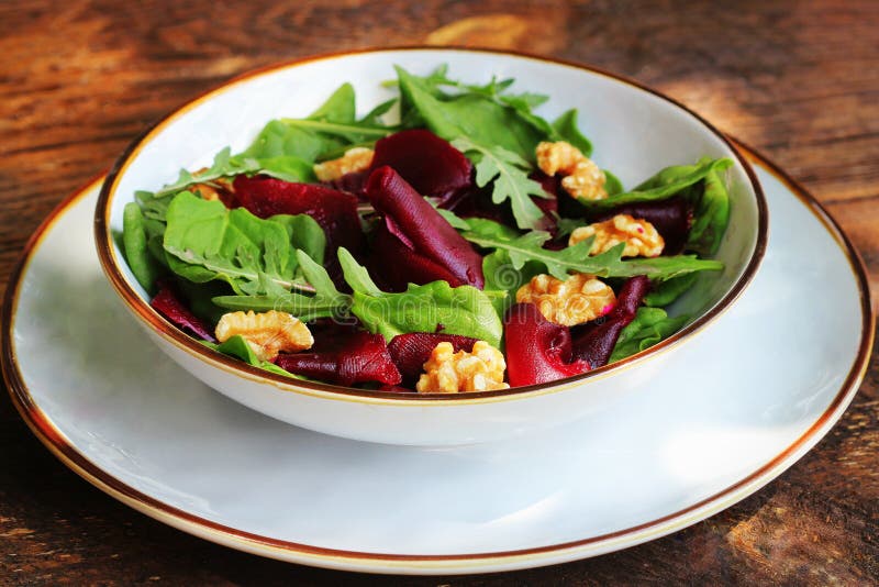 Gezonde Bietensalade met verse zoete babyspinazie, arugula, noten op houten achtergrond stock afbeeldingen Gezonde Bietensalade met verse zoete babyspinazie, arugula, noten op houten achtergrond stock afbeeldingen