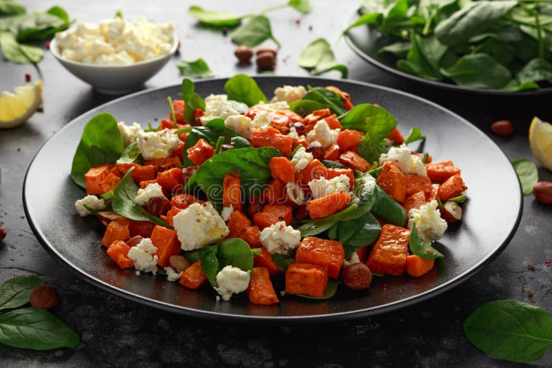 Gezonde geroosterde bataatsalade met spinazie, feta-kaas, hazelnootnoten in zwarte plaat royalty-vrije stock foto's Gezonde geroosterde bataatsalade met spinazie, feta-kaas, hazelnootnoten in zwarte plaat royalty-vrije stock foto's