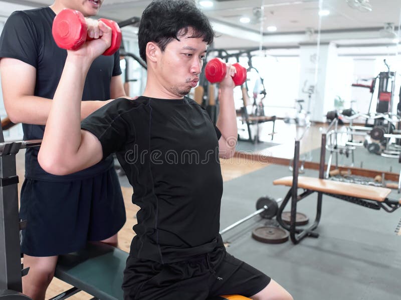 Gezonde jonge Aziatische mensen opheffende domoor met persoonlijke trainer bij sportgymnastiek Geschiktheid en trainingconcept royalty-vrije stock fotografie Gezonde jonge Aziatische mensen opheffende domoor met persoonlijke trainer bij sportgymnastiek Geschiktheid en trainingconcept royalty-vrije stock fotografie