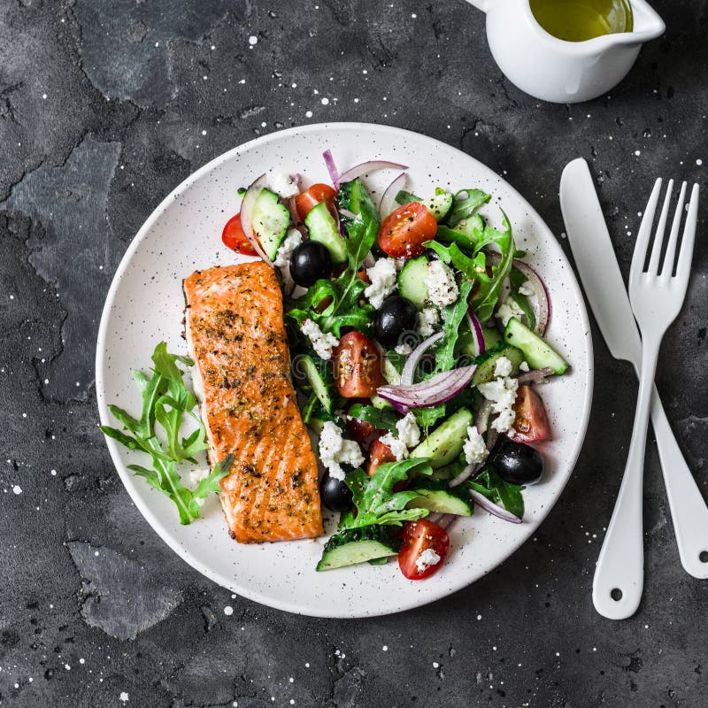 Gezonde mediterrane lunch - geroosterde filetzalm en groenten, olijven, de Griekse salade van feta op donkere achtergrond, hoogst stock foto Gezonde mediterrane lunch - geroosterde filetzalm en groenten, olijven, de Griekse salade van feta op donkere achtergrond, hoogst stock foto