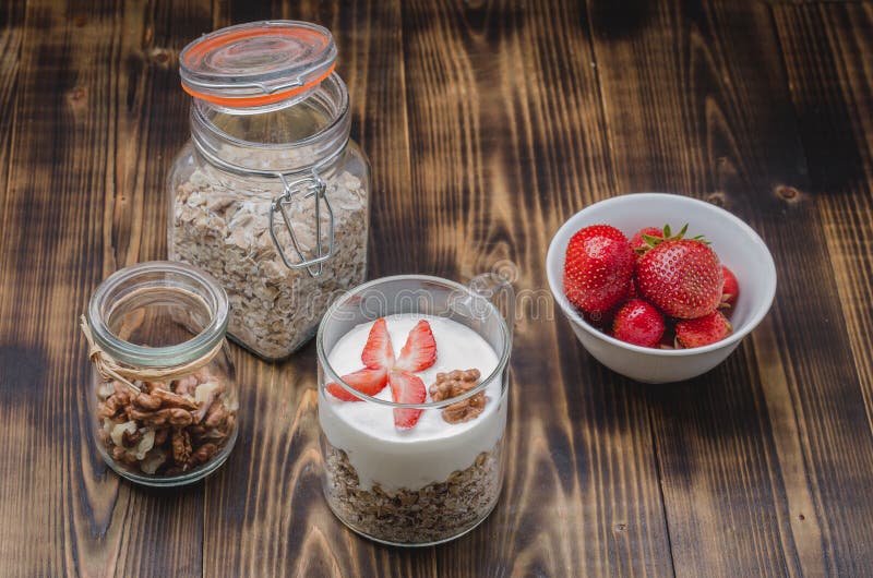Gezonde ontbijtyoghurt, verse aardbei, eigengemaakte granola en okkernoot in open glaskruik op een houten lijst stock foto's Gezonde ontbijtyoghurt, verse aardbei, eigengemaakte granola en okkernoot in open glaskruik op een houten lijst stock foto's