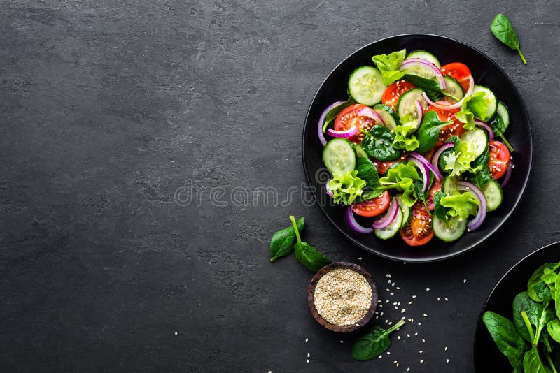 Gezonde plantaardige salade van verse tomaat, komkommer, ui, spinazie, sla en sesam op plaat Dieetmenu