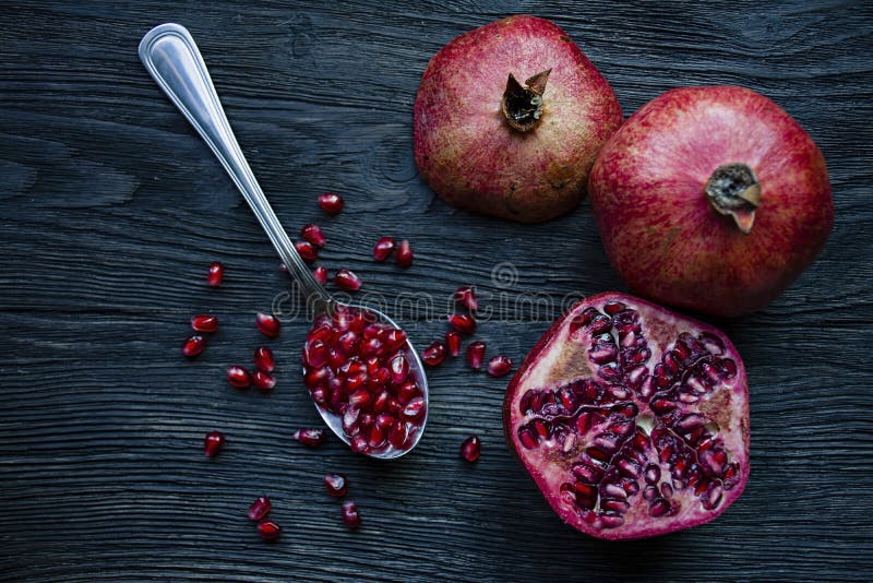Gezonde verse granaatappels op een donkere houten achtergrond Een lepel met korrels van verse granaatappel Trillende nadruk Donke stock afbeeldingen Gezonde verse granaatappels op een donkere houten achtergrond Een lepel met korrels van verse granaatappel Trillende nadruk Donke stock afbeeldingen