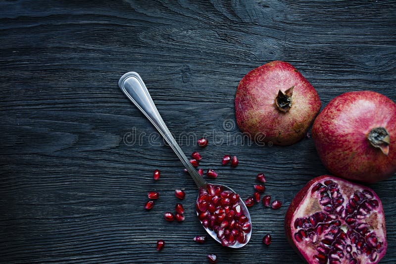 Gezonde verse granaatappels op een donkere houten achtergrond Een lepel met korrels van verse granaatappel Trillende nadruk Donke royalty-vrije stock foto Gezonde verse granaatappels op een donkere houten achtergrond Een lepel met korrels van verse granaatappel Trillende nadruk Donke royalty-vrije stock foto