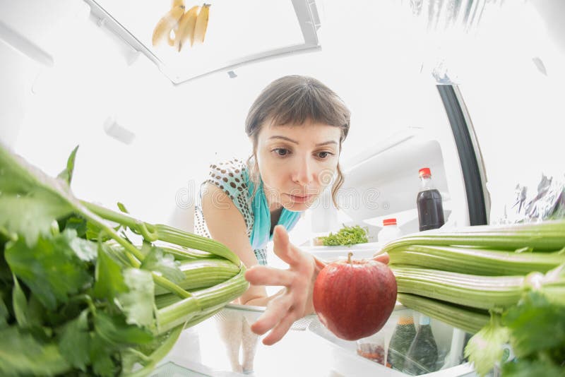 Gezonde voeding: Een hand die een appel van het open ijskasthoogtepunt grijpen van greens royalty-vrije stock afbeeldingen Gezonde voeding: Een hand die een appel van het open ijskasthoogtepunt grijpen van greens royalty-vrije stock afbeeldingen