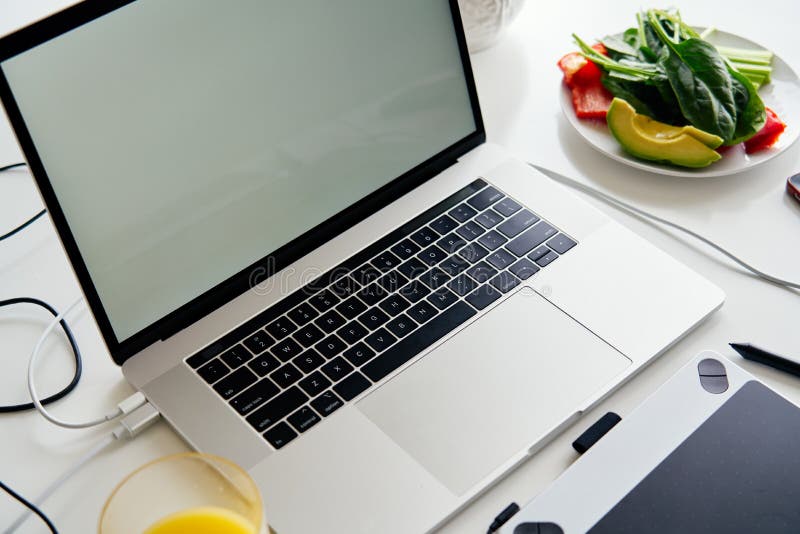 Geöffneter Laptop, Grafiktablette und Frühstück mit Saft auf weißer Tabelle, leerer Schirm für Modellentwurf lizenzfreies stockfoto