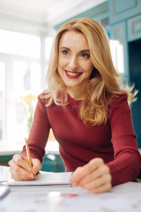 Geïnspireerde vrouw die in haar notitieboekje en het denken schrijven stock afbeelding Geïnspireerde vrouw die in haar notitieboekje en het denken schrijven stock afbeelding