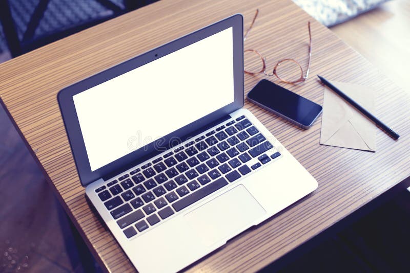 Geöffnete Laptop-Computer mit Raum des leeren Bildschirms für Entwurf, Handy, Gläser, Umschlag Café oder mit-arbeitender Arbeitsp lizenzfreies stockbild