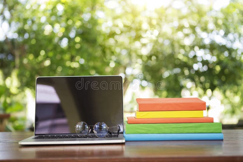 Geöffneter Laptop mit den Gläsern und Büchern gestapelt auf hölzerner Tabelle mit stockfotos Geöffneter Laptop mit den Gläsern und Büchern gestapelt auf hölzerner Tabelle mit stockfotos