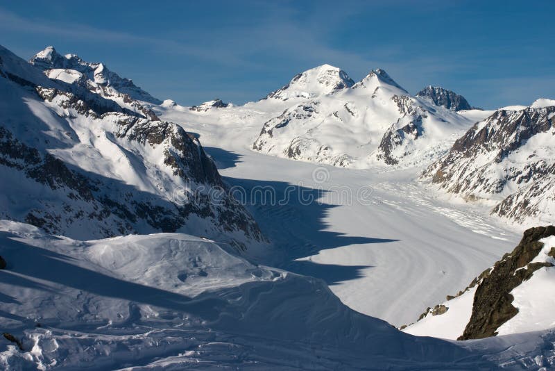 Winter in the Swiss Alps. View over the Aletsch Glacier from Moosfluh, Bettmeralp, Brig Wallis-Valais Switzerland. Sunny day, long shadows. Views of the Monch, Eiger, Jungfrau. Winter in the Swiss Alps. View over the Aletsch Glacier from Moosfluh, Bettmeralp, Brig Wallis-Valais Switzerland. Sunny day, long shadows. Views of the Monch, Eiger, Jungfrau