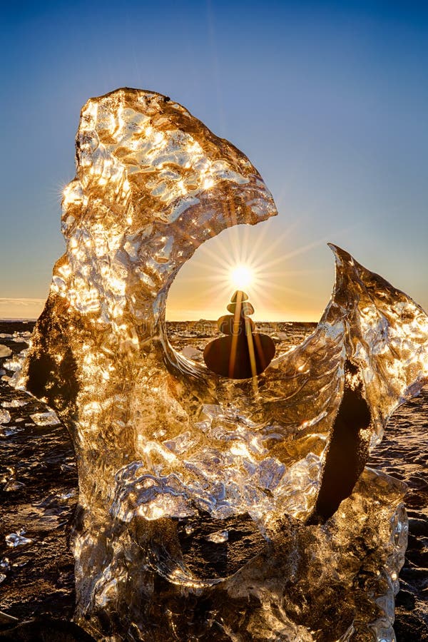 Ghiacciaio e rocce equilibrate con la stella del sole su Diamond Beach dell'Islanda con la sabbia nera