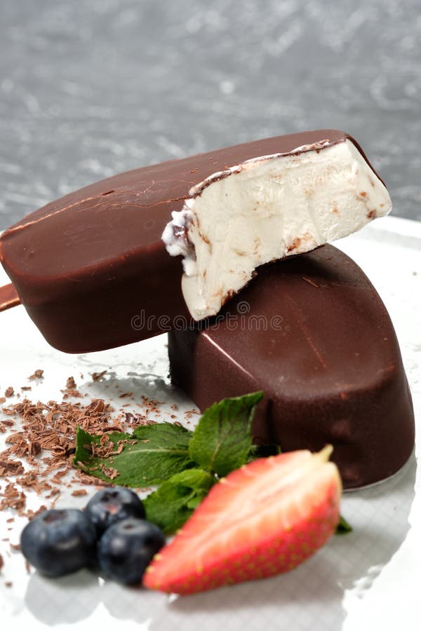 Ghiaccioli del gelato del burro del cioccolato sul piatto bianco con le bacche fresche di estate, fragole, mirtilli immagine stock libera da diritti Ghiaccioli del gelato del burro del cioccolato sul piatto bianco con le bacche fresche di estate, fragole, mirtilli immagine stock libera da diritti