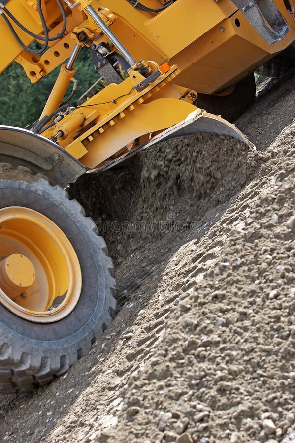 Industrial machine moving gravel on a new road. Industrial machine moving gravel on a new road