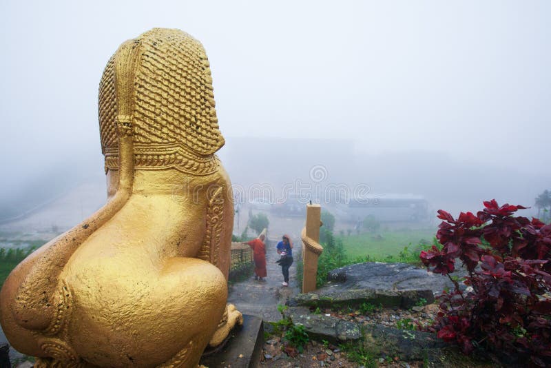 Giant gold statue of Singha Khmer, monk, and tourist in the mist stock image Giant gold statue of Singha Khmer, monk, and tourist in the mist stock image