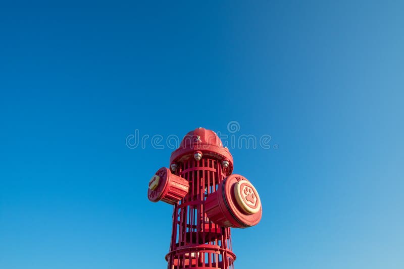 A Giant Red Fire Hydrant at a Dog Park on a Clear Blue Sky