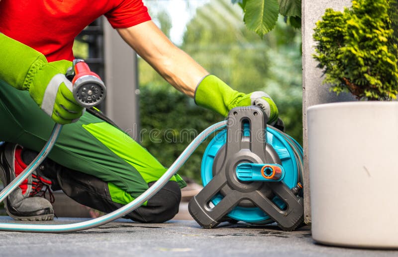 Giardiniere che utilizza una bobina per impianti di irrigazione fotografie stock