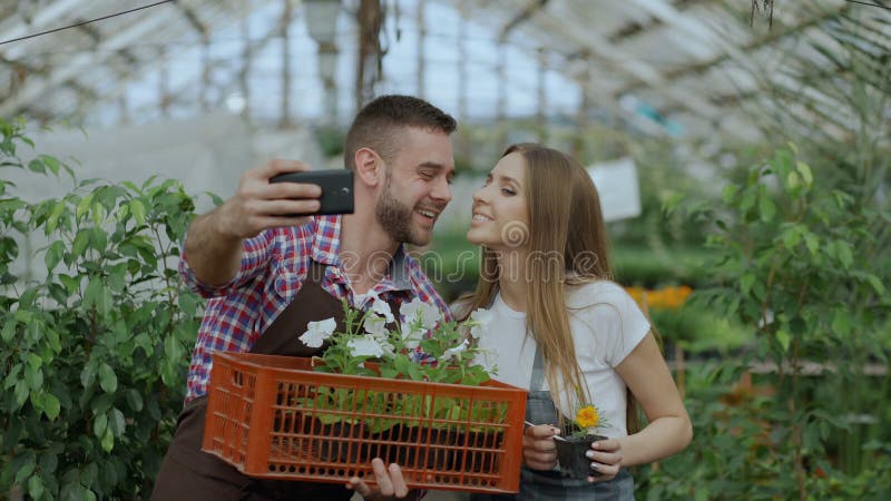 Giardinieri amorosi allegri delle coppie che prendono l'immagine del selfie sulla macchina fotografica dello smartphone e che bac