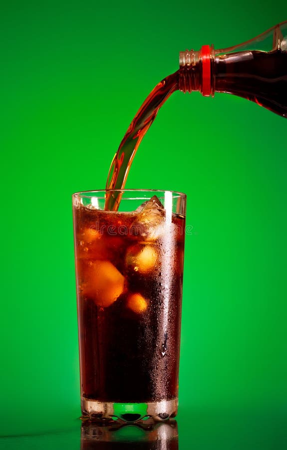 Pouring cola in glass over green background. Pouring cola in glass over green background