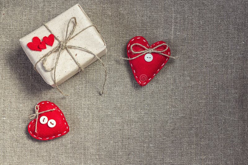 Gift box with a natural rope and two red hearts on sacking