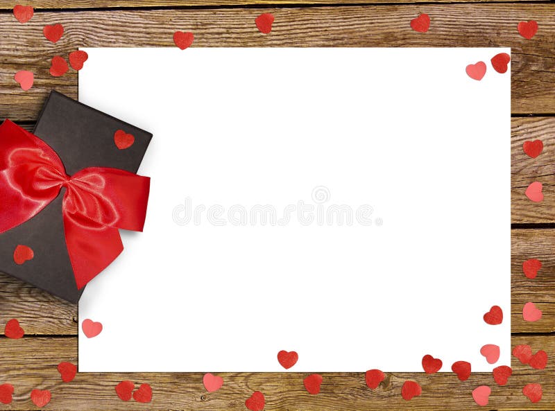 Gift box with red bow ribbon and paper heart on wooden background for Valentines day