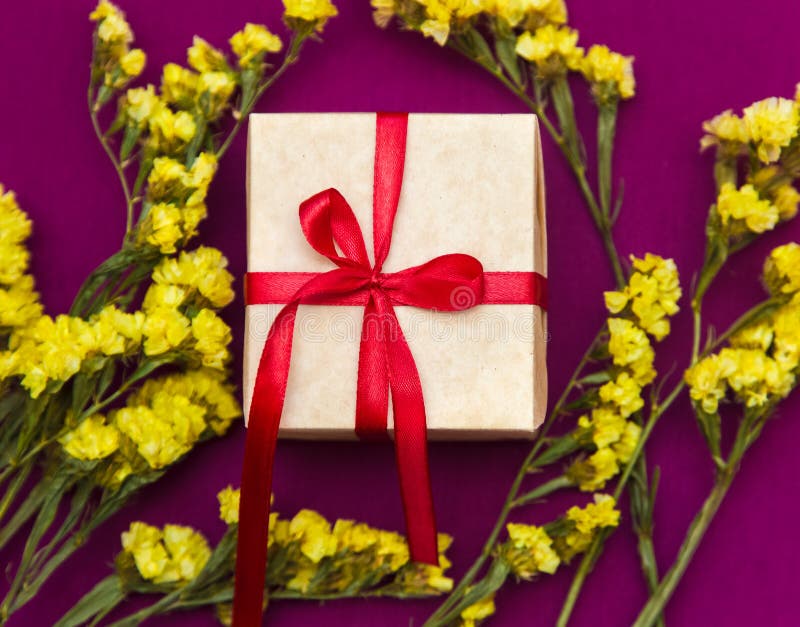 Gift Box with Red Ribbon Surrounded by Yellow Flowers Stock Photo Image of color, greeting
