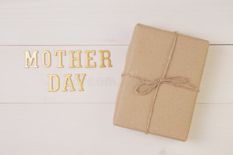 Gift box and text is mother day on wooden background with romantic, presents word and message pastel tone, package with congratulation with happy, spring or summer nature on desk, holiday concept