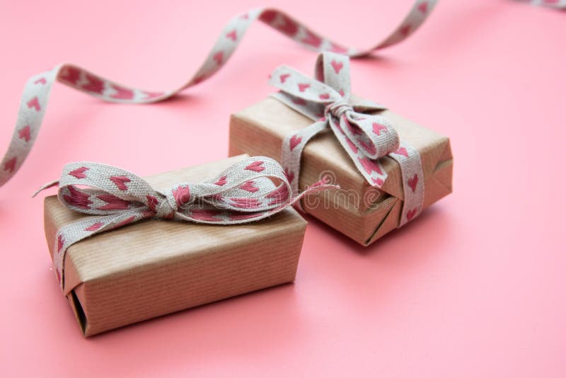 Gift box wraped in kraft paper and bow, on pink background. Valentine& x27;s Day, Birthday, Party concept