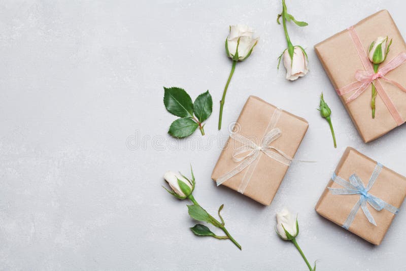 Gift or present box wrapped in kraft paper and rose flower on gray table from above. Flat lay styling. Copy space for text. royalty free stock image Gift or present box wrapped in kraft paper and rose flower on gray table from above. Flat lay styling. Copy space for text. royalty free stock image